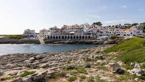 A coastal town with white buildings, rocky shoreline, and a clear sky. - Binilaya - Charming 3-bedroom house - seafront (Binibèquer Nou)