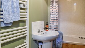 Een badkamer met een wit wastafel, een douchegordijn en een handdoekrek met een blauwe handdoek.