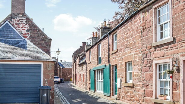 Een smalle, geplaveide straat met aan weerszijden traditionele bakstenen gebouwen, een combinatie van woningen en bedrijven.