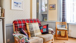 Een gezellige woonkamer met een bank, een houten stoel en een raam met gordijnen.
