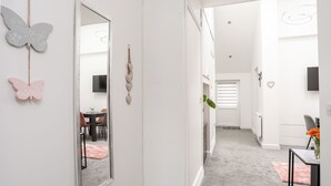 A hallway with a large mirror, a dining area with a table and chairs, and a staircase leading to another room. - Beeches Bach (Prestatyn)