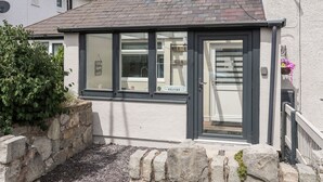 A small, modern house with a dark roof, large windows, and a welcoming sign. - Beeches Bach (Prestatyn)
