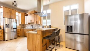 Une cuisine moderne avec des meubles en bois, des appareils en acier inoxydable et un îlot central doté de tabourets de bar.