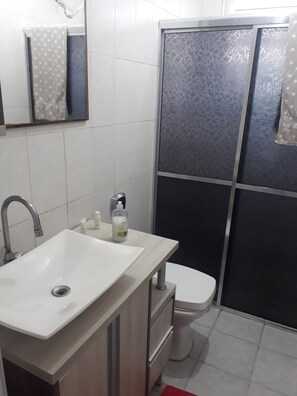 Chuveiro, secador de cabelo, toalhas de banho, papel higiênico