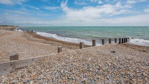 A pebble beach with a wooden walkway leading to the sea. - A stunning two-level seaside retreat with incredible sea views. (East Preston, West Sussex Coast)