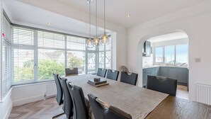 A modern dining area with a large table, multiple chairs, and pendant lighting. - A stunning two-level seaside retreat with incredible sea views. (East Preston, West Sussex Coast)