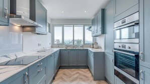 A modern kitchen with grey cabinets, a herringbone wood floor, and built-in appliances. - A stunning two-level seaside retreat with incredible sea views. (East Preston, West Sussex Coast)
