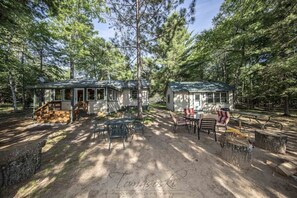 Een chalet met een veranda, buitenzitplaatsen en een picknicktafel in een bebost gebied.