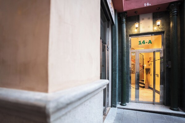 A hotel entrance with a glass door, a sign reading "14-A", and a staircase leading inside.