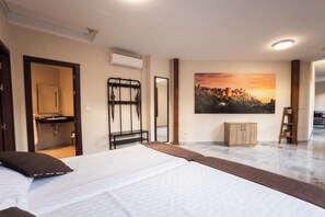 A bedroom with a bed, a bathroom, a painting of a sunset, and a wooden cabinet. - Apartamentos Reyes Católicos (Granada)