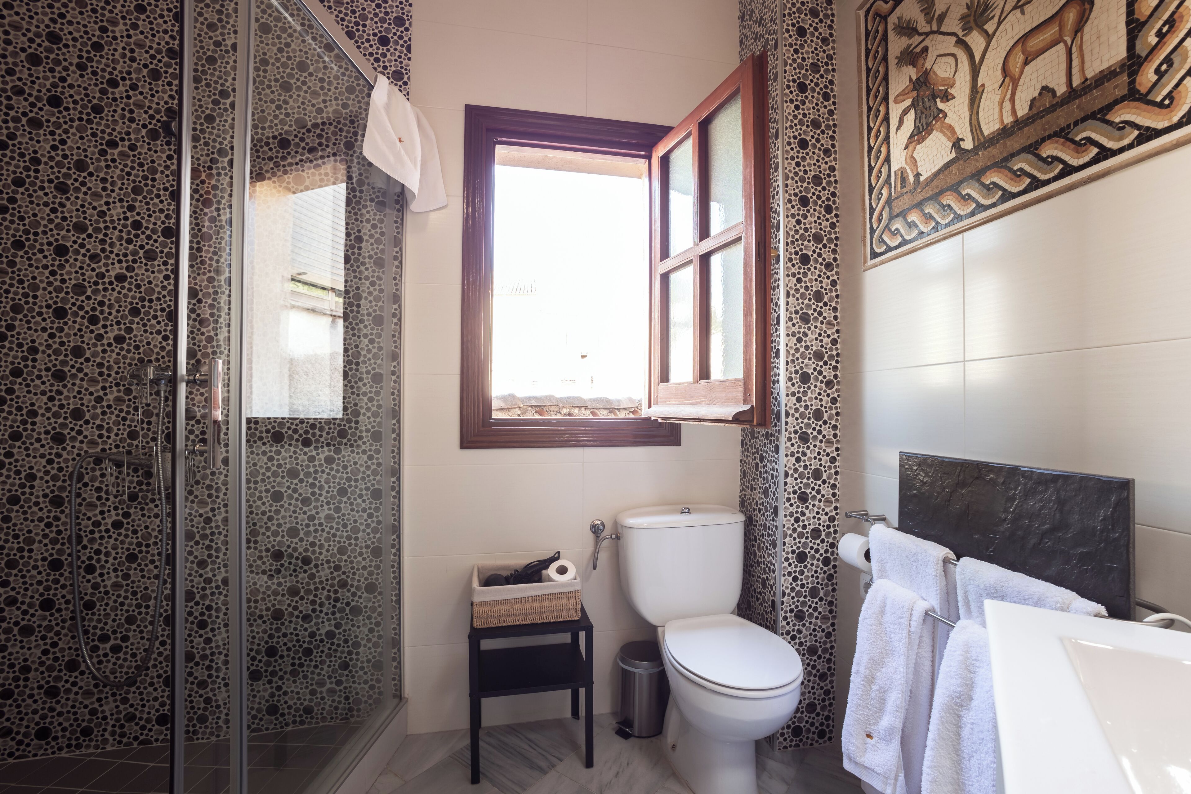 Une salle de bain avec une douche, des toilettes et une fenêtre.