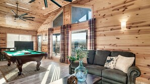 A wooden interior with a pool table, a sofa, and a vase with flowers.