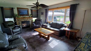 A living room with a fireplace, leather sofas, a coffee table, and a ceiling fan.