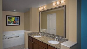 Une salle de bain avec un meuble-lavabo à deux vasques, un grand miroir et une baignoire.