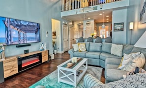 A spacious living room with a large flat-screen TV, a fireplace, a sofa, and a dining area with chairs.