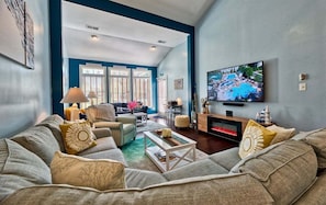 A living room with a large TV, comfortable seating, and a fireplace.