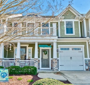 A two-story house with a front porch, a garage, and a welcome sign.