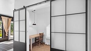 Una habitació amb una porta corredissa d'estil shoji, taula de menjador de fusta amb cadires i una làmpada penjant.