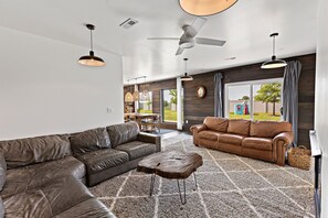 A modern living room with a sectional sofa, a coffee table, and a ceiling fan.