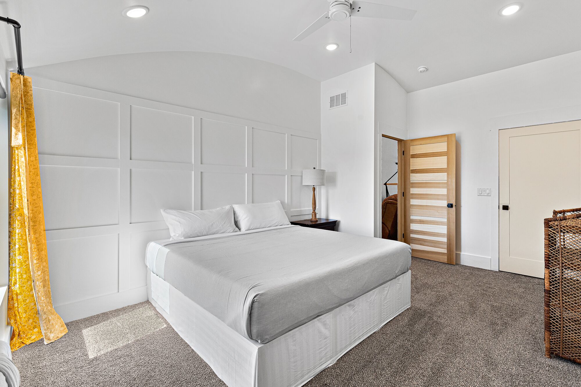A modern bedroom with a bed, a nightstand, a lamp, and a wardrobe.
