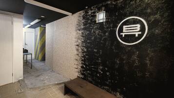 A corridor with a bench, a wall with a circular logo, and a door leading to another room.