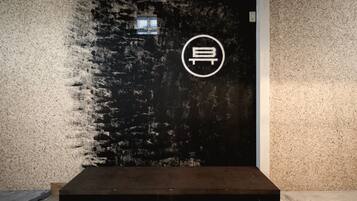 A dark wall with a textured surface and a circular logo.