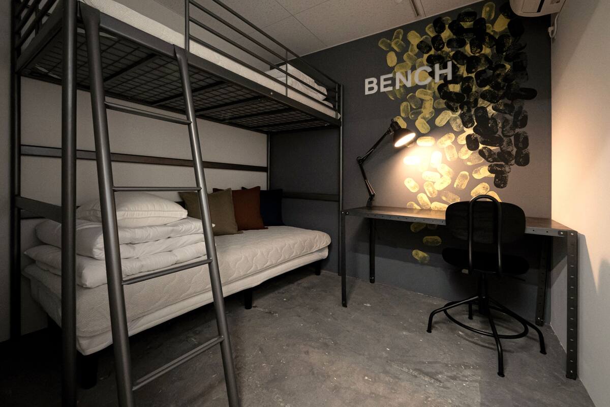 A bunk bed room with a desk and a lamp.