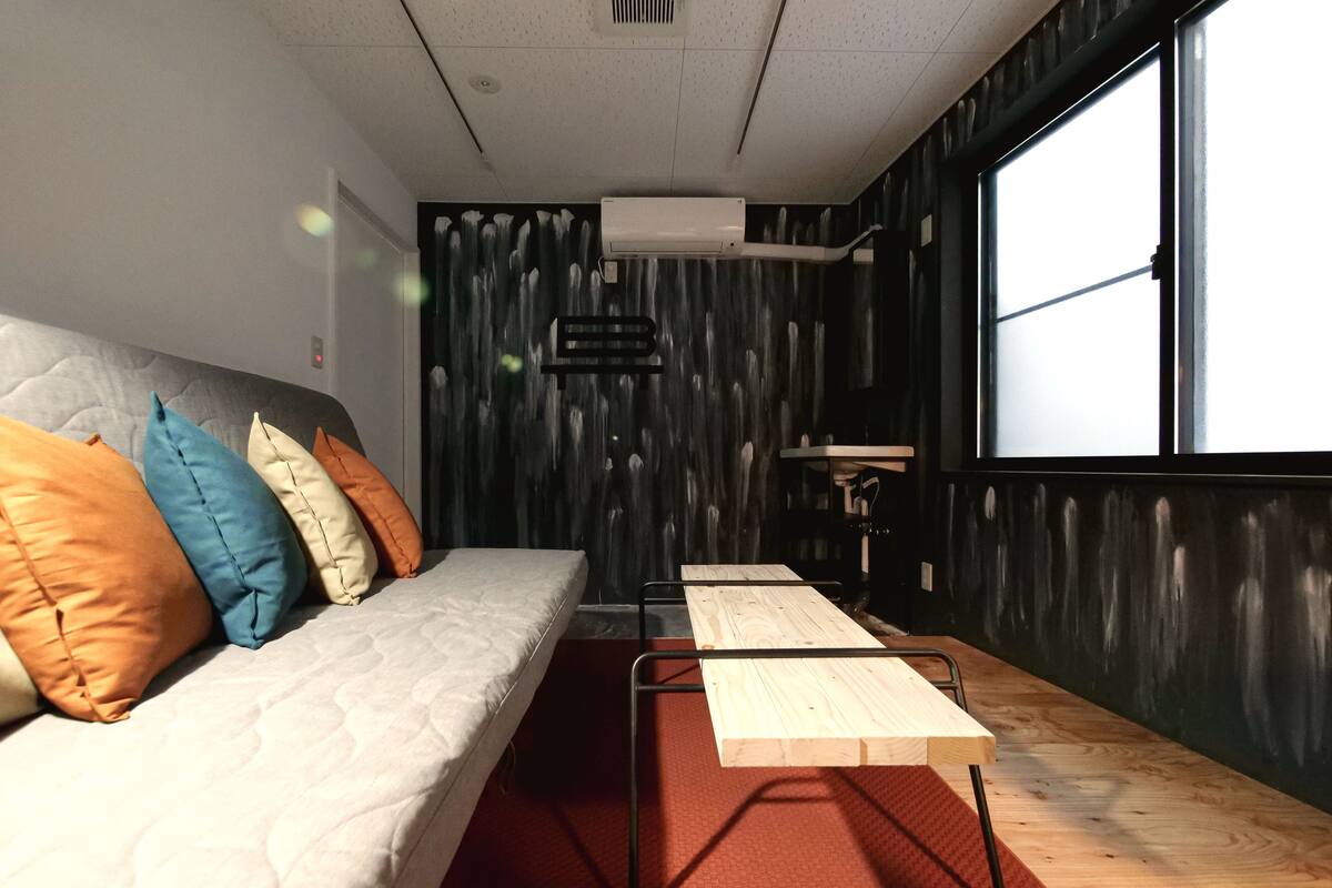 A modern room with a sofa, pillows, a wooden table, and a window.