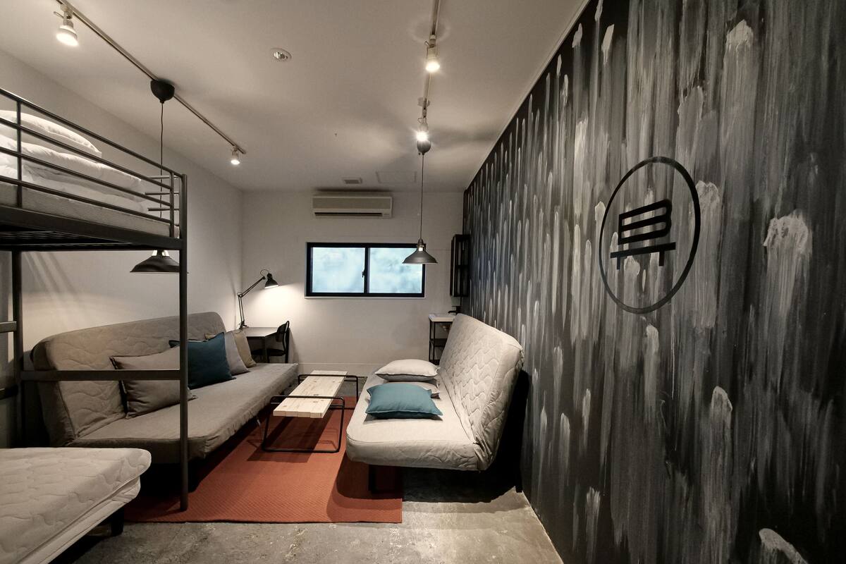 A compact room with bunk beds, a sofa, a desk, and a chair.
