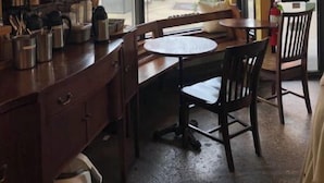 Un restaurante acogedor con un ventanal grande, una barra de madera y una mesa con sillas.