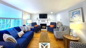 A living room with a blue sofa, patterned armchairs, a wooden coffee table, and a fireplace. - Short 1/2 mile walk to the beach! Located in beautiful Harwich. (Harwich)