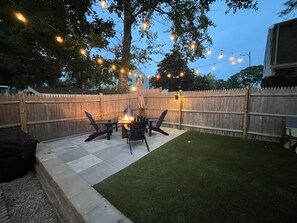 A backyard patio with a fire pit, outdoor furniture, and string lights. - Short 1/2 mile walk to the beach! Located in beautiful Harwich. (Harwich)