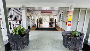 A hotel lobby with a staircase, a reception desk, and a view of the outdoor area.