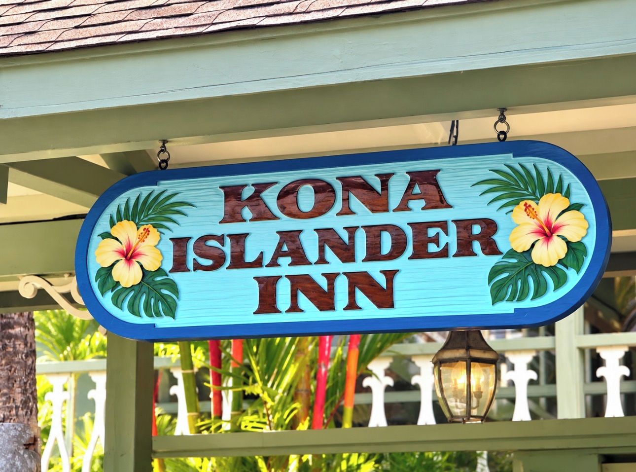 Señal para Kona Islander Inn con decoraciones florales tropicales.