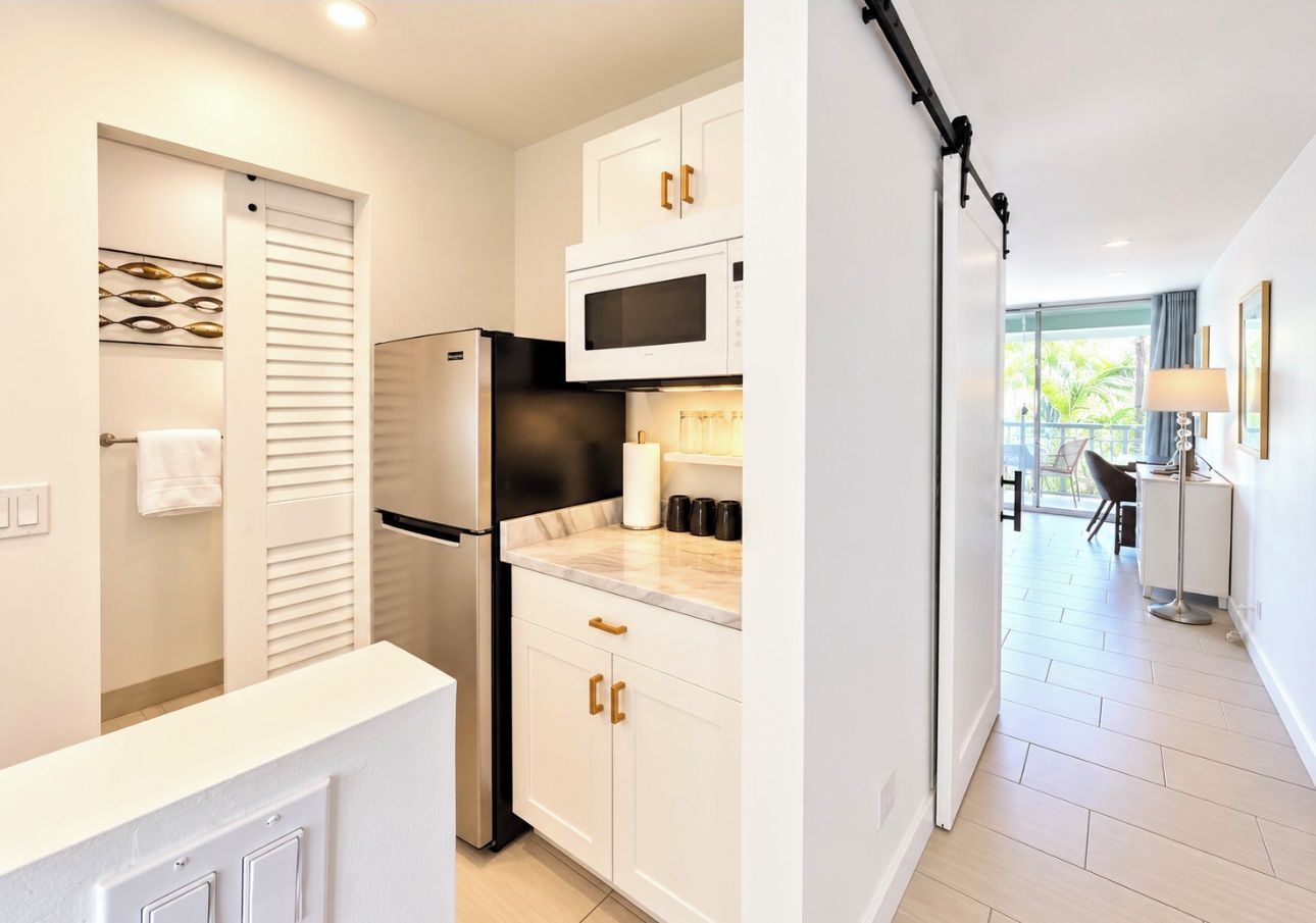 A modern kitchen with white cabinetry, a stainless steel refrigerator, and a microwave.