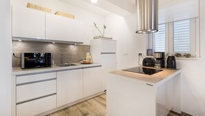 Una cucina moderna con mobili bianchi, un forno a microonde integrato e una macchina da caffè sul piano di lavoro.