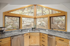 Una cocina con encimera de piedra, armarios de madera y un lavamanos empotrado.