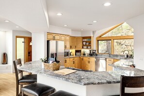 Una cocina moderna con encimeras de granito, armarios de madera y una isla grande con taburetes de bar.