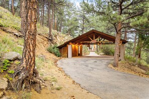 A cabin with a wooden roof and a dirt path leading to it, surrounded by trees.