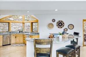 A modern kitchen with a central island, wooden cabinetry, and a stone backsplash.