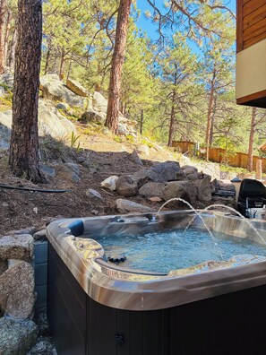 A hot tub with a waterfall feature, surrounded by rocks and trees.