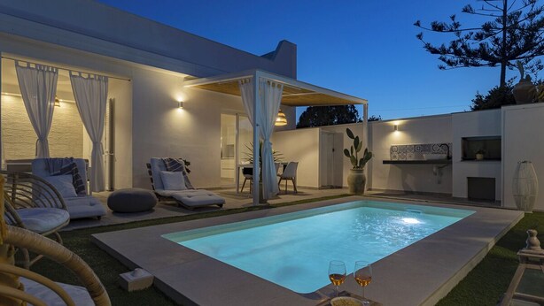 A modern outdoor pool area with lounge chairs and a dining setup. - Tocco di Blu  SicilyMyHome (Santa Maria del Focallo)