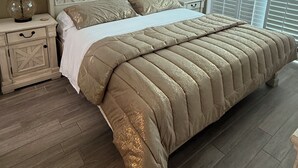 A bedroom with a bed, nightstands, a ceiling fan, and a window with blinds. - Gorgeous, oceanfront 2/2 villa in upscale Blue Water Keys North Myrtle Beach (North Myrtle Beach)