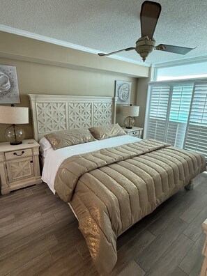 A bedroom with a bed, nightstands, a ceiling fan, and a window with blinds.