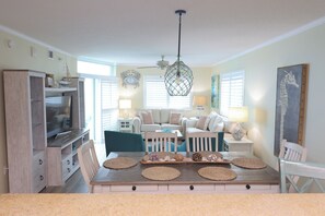 A living room with a TV, seating, and a dining area with placemats.