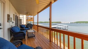 Une terrasse couverte, aménagée avec des meubles en osier, et offrant une vue sur un lac.
