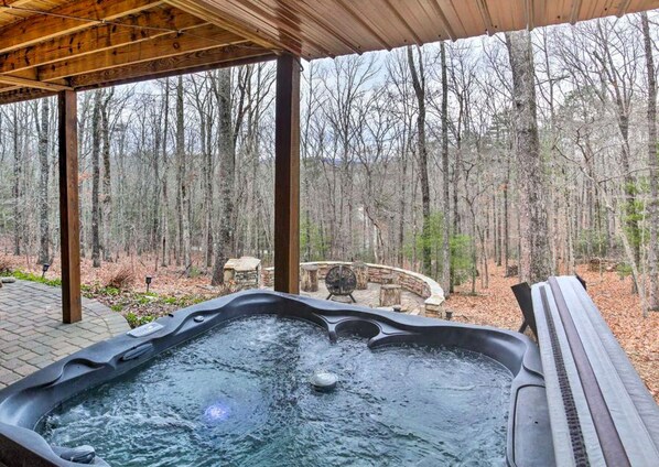 Un bain à remous situé dans un espace extérieur abrité, avec vue sur une forêt.