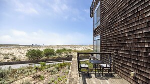 A balcony with two chairs and a table, overlooking a beach and dunes. - Pelican 54: Relax with an ocean view. (Pajaro Dunes)