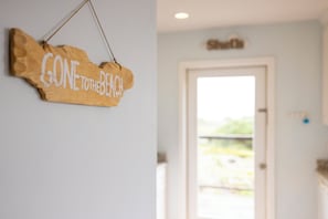 A wooden sign with the text 'GONE TO THE BEACH' hanging on a wall.