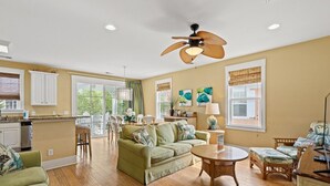 A spacious living room with a green sofa, a round coffee table, and a dining area with a wooden table and chairs. - Spa Villa home N Beach resort &spa 2 min to beach 7 pools attractions allow pet (North Myrtle Beach)